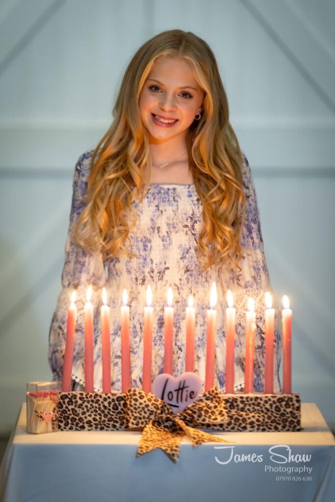 Young girl with lit candles on a menorah with 'Lottie' written over leopard print.