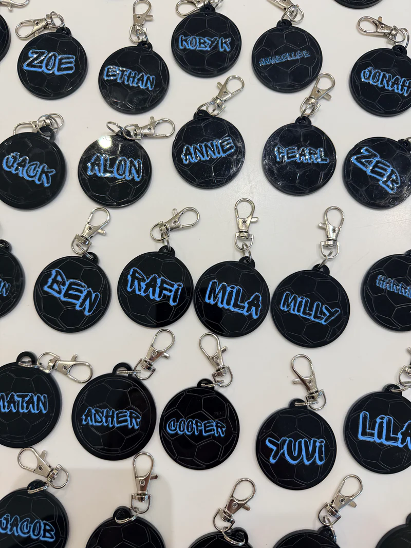 Black_round_keyrings_with_blue_personalised_name_text_on_a_white_background