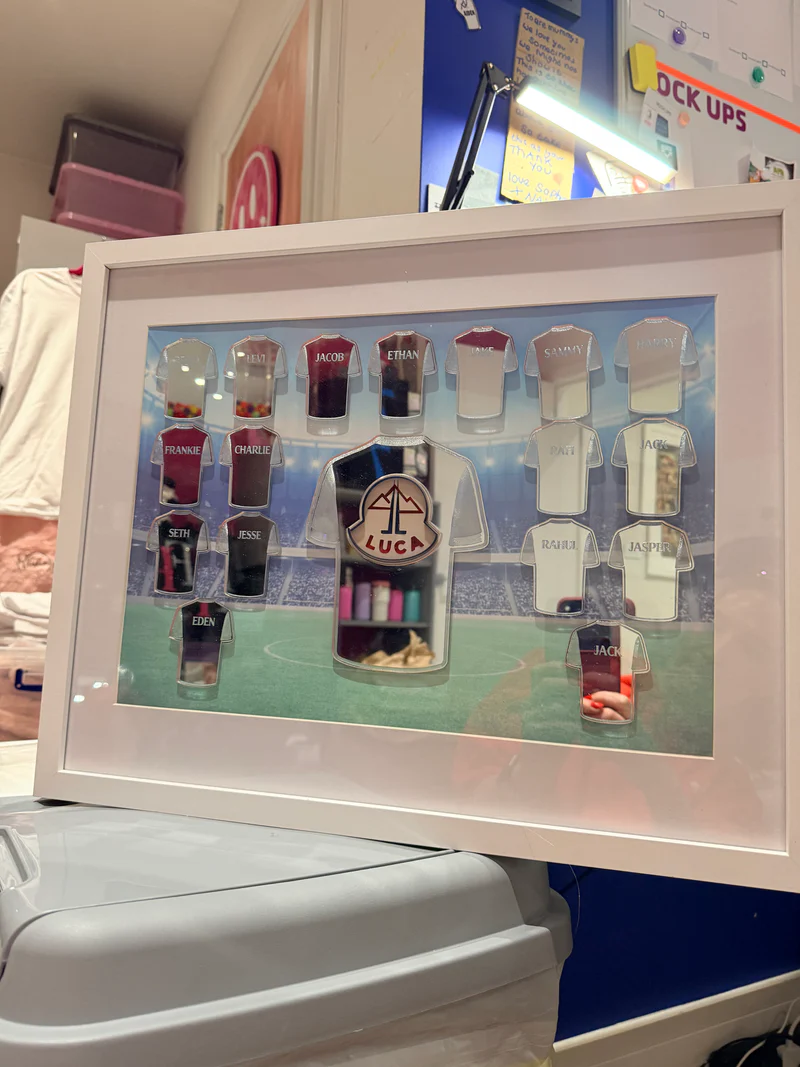 Framed_football_gift_with_various_small_acrylic_shirts_with_engraved_names_on_a_blue_background