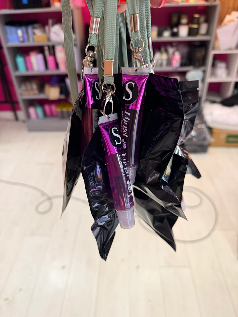 Purple_lip_gloss_keyrings_with_silver_cap_on_a_reflective_surface_blurred_background
