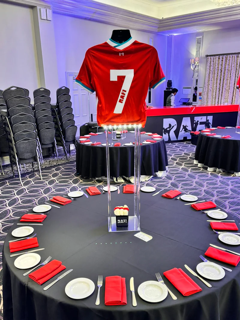 Table_centre_with_red_and_white_plates_and_napkins_with_a_red_football_shirt_and_personalised_name_as_the_table_centre
